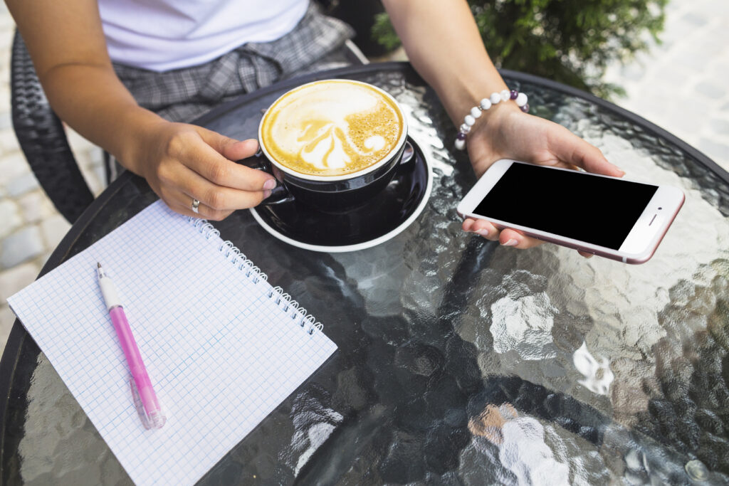 woman drinking coffee holding smartphone